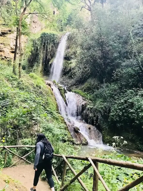 Elaina walking by a waterfall in Villa Gregoriana on a day trip from Rome to Tivoli