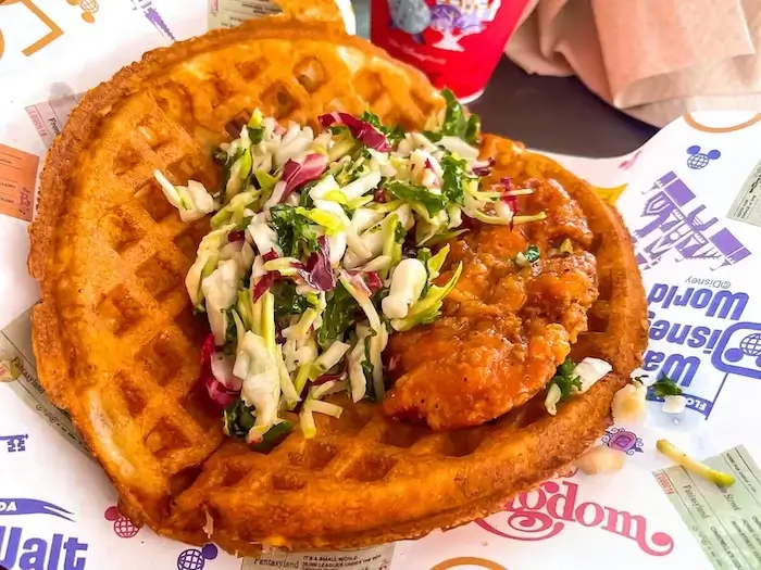 large folded waffle with fried chicken and cabbage mix inside
