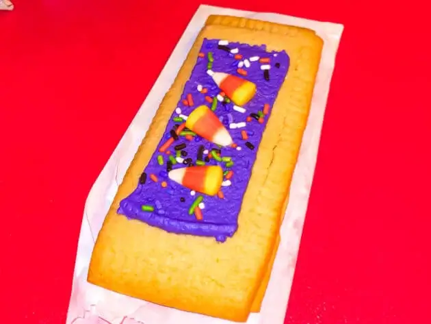 A large "fancy" lunch box tart with purple frosting and candy corn from Woody's lunchbox in Disney World.