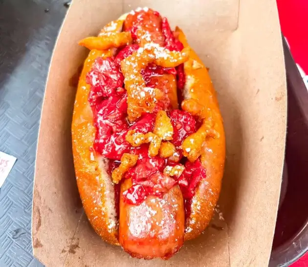 Hot dog with strawberry bacon jam and funnel cake pieces in Disney World