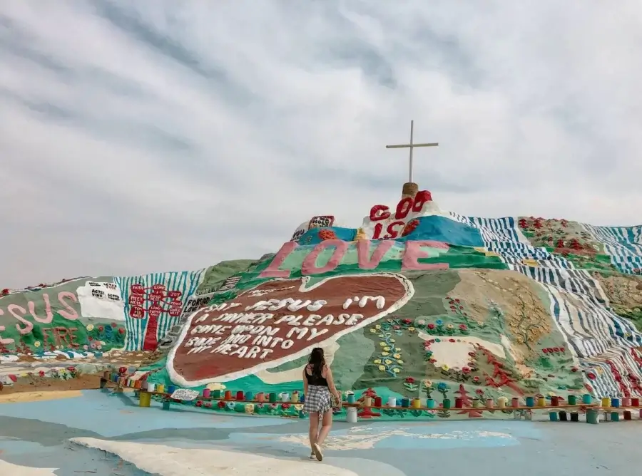 Elaina looking up in awe at Salvation Mountain, the most well-known Slab City art installation