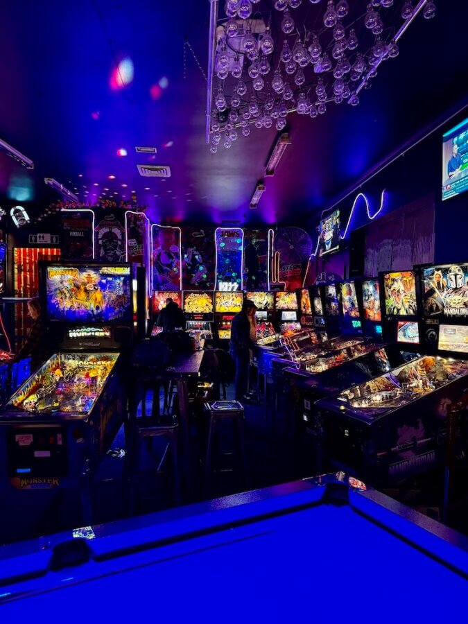A pool table and several pinball machines inside Beercade Australia in Sydney