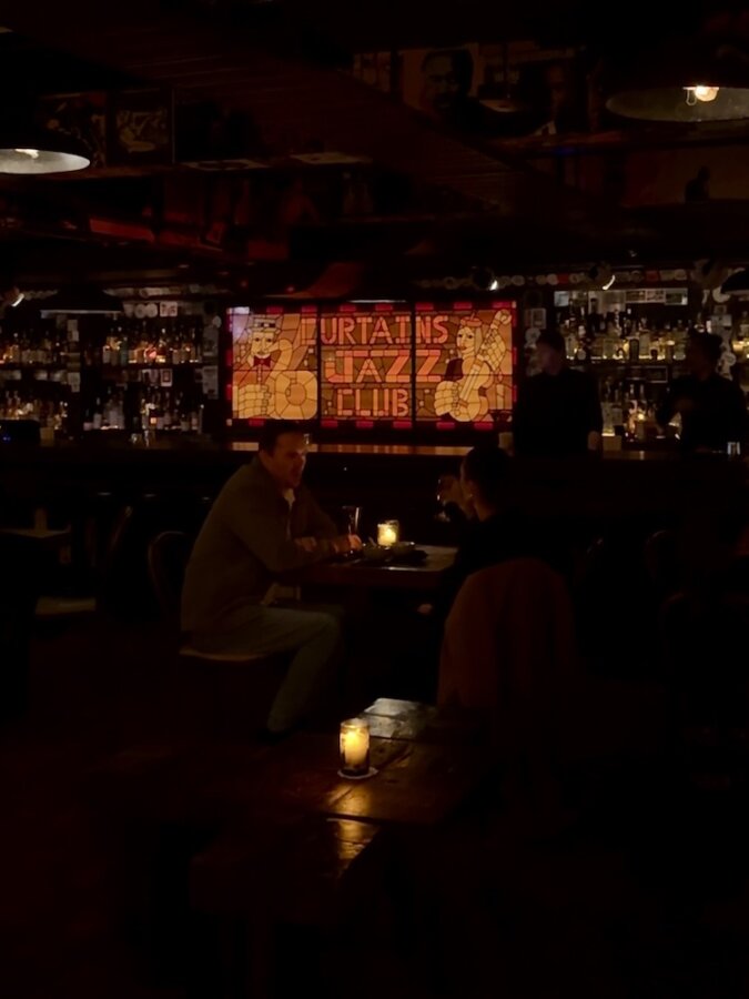 The bar and a lighted sign that says "Curtains Jazz Club"