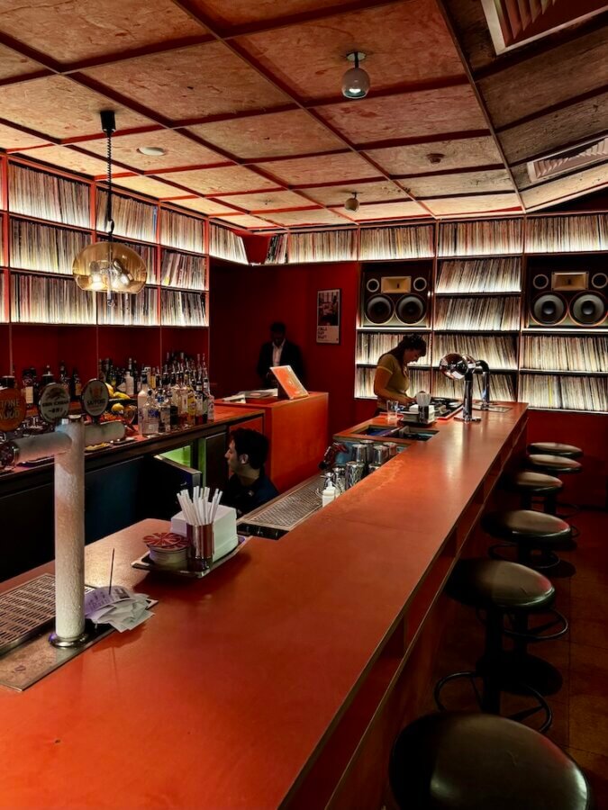 An orange bar with bar stools and shelves full of records surrounding it at JAM Record Bar in Sydney